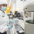 NanoLab intern stands near equipment in a lab wearing PPE